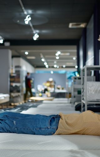 Woman choosing bed mattress in furniture store